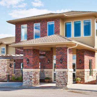 A modern two-story building featuring brick and stone elements with large windows.