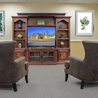 A cozy living room setup with an entertainment center, television, and two armchairs.
