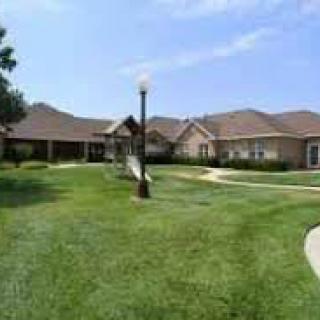 A suburban house with a well-maintained lawn and a pathway leading to the entrance under a clear blue sky.