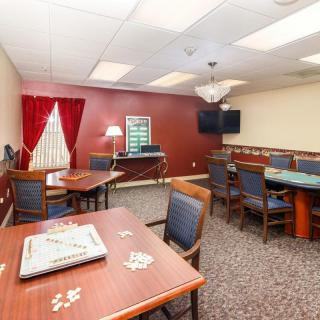 A cozy game room with tables and puzzles, featuring a television and comfortable seating.