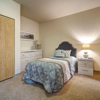 A cozy bedroom with a single bed, nightstand, and dresser in neutral tones.
