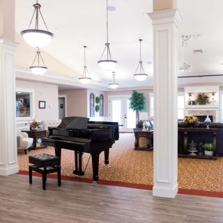 A spacious living room with a grand piano and elegant decor.
