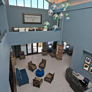 A spacious and modern lobby with a high ceiling, featuring stylish furniture and unique lighting fixtures.
