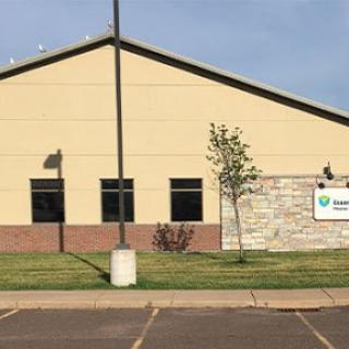 A commercial building with a modern design, featuring large windows and a landscaped area in front.