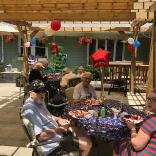A group of people enjoying a festive outdoor gathering on a patio, surrounded by colorful decorations and food.