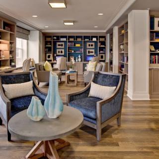A cozy living room with armchairs and bookshelves, featuring decorative vases on a wooden table.