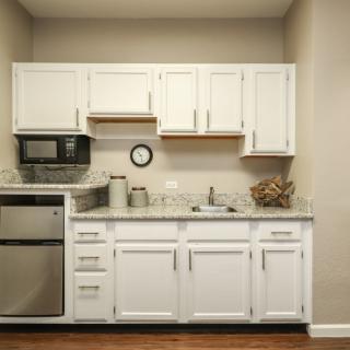 A small kitchen with white cabinets, a microwave, and a sink.