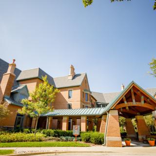 A beautiful brick building with a sloped roof and inviting entrance, surrounded by greenery.