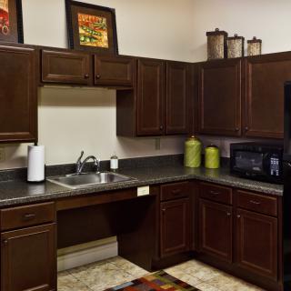 A cozy kitchen featuring dark wooden cabinets and a black countertop with neatly arranged appliances.
