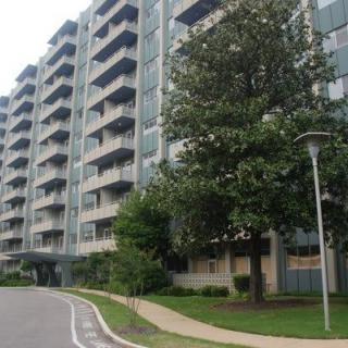 A multi-story apartment building with balconies and surrounding greenery.