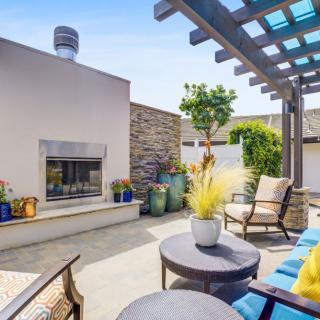 A cozy outdoor patio with comfortable seating, a modern fireplace, and lush greenery.