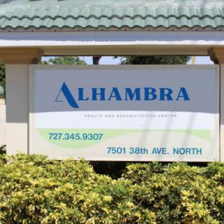 A photo of a sign displaying the name 'Alhambra' along with contact information and an address.