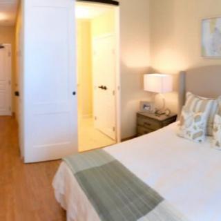 Cozy bedroom with a neatly made bed and a bedside lamp.