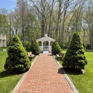 A scenic pathway leading to a charming gazebo surrounded by lush greenery.