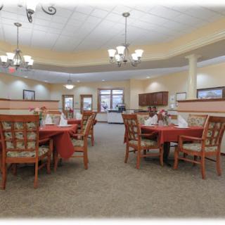 A spacious and elegantly decorated dining room with neatly arranged tables and chairs under chandeliers.