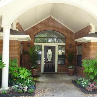 A welcoming brick house entrance with a front porch and various plants.