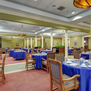An empty dining room with blue tablecloths and wooden chairs.