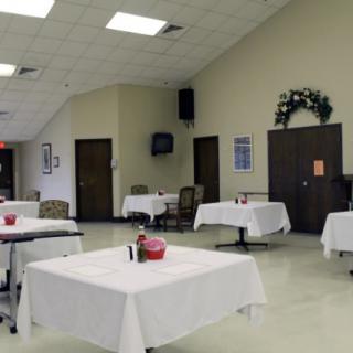 An empty dining room with tables covered in white tablecloths.