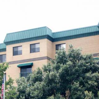 A building with a green roof, surrounded by trees and featuring an American flag.