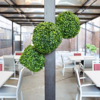 A modern dining area featuring decorative artificial greenery clusters mounted on a pole.