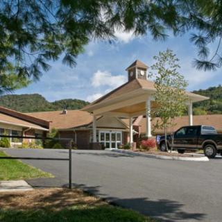 A building entrance surrounded by trees and mountains on a sunny day.
