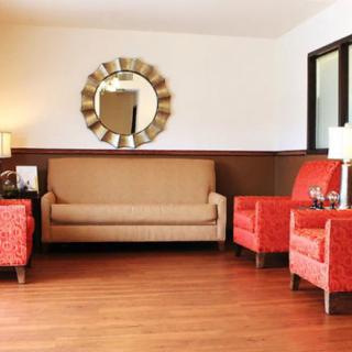A cozy living room with a beige sofa, red chairs, and decorative elements like a mirror and lamps.