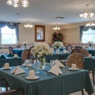 An elegant dining room with tables set with teal tablecloths and floral centerpieces.