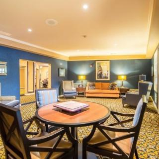 A cozy and elegant living room featuring a seating area with a round table, comfortable chairs, a sofa, and ambient lighting.