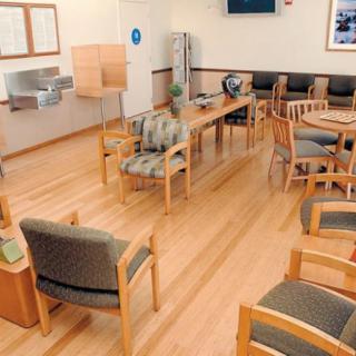 An empty waiting room with chairs and tables arranged in a healthcare facility.
