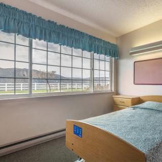 A serene hospital room featuring a single bed and large windows overlooking a scenic view.