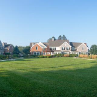 A picturesque view of modern homes set against a clear blue sky, featuring a lush green lawn.