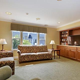 A cozy living room with patterned sofas, a built-in bookshelf, and large windows letting in natural light.