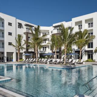 A luxurious hotel with a large swimming pool surrounded by palm trees.