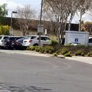 A view of a parking lot with several cars parked and a building in the background.