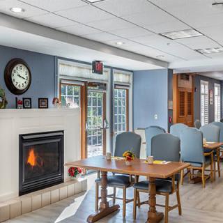 A cozy living and dining area featuring a fireplace, tables with chairs, and large windows.