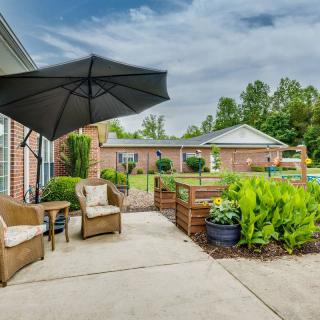 A cozy outdoor patio area with seating, an umbrella, and surrounding greenery.