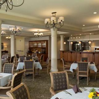 An elegant restaurant dining room with neatly arranged tables and chairs, complemented by chandeliers.