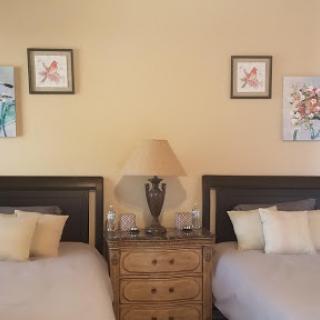A cozy bedroom featuring twin beds, decorative artwork on the walls, and a stylish lamp on the nightstand.