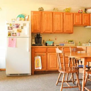 A cozy kitchen with wooden cabinets, a dining table, and a white refrigerator.