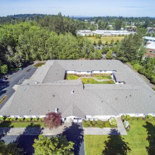 Aerial view of a large building with a central courtyard surrounded by trees and greenery.