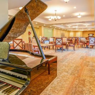 An elegant dining room featuring a grand piano and stylish seating arrangements.