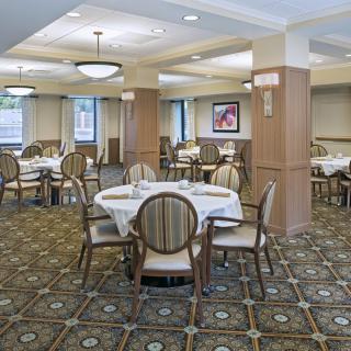 A well-decorated dining room with round tables, upholstered chairs, and ambient lighting.