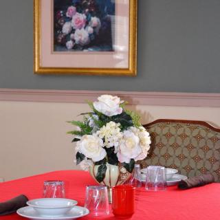 A dining table elegantly set with white flowers and framed artwork on the wall.