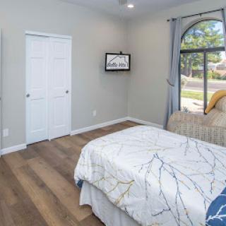 A cozy and modern bedroom featuring light-colored walls and wooden flooring.