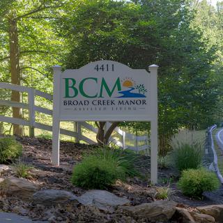 Entrance sign for Bridal Creek Marina surrounded by trees and greenery.