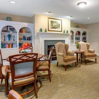 A cozy living area featuring a fireplace, bookshelves, and comfortable chairs around a table.