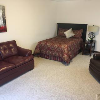 A cozy bedroom with a bed, sofa, and lamp.