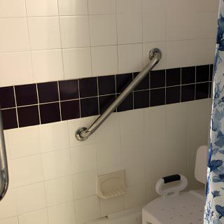 A bathroom with a grab bar installed on tiled walls for safety.
