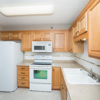 A modern kitchen featuring wooden cabinets, a countertop, and essential appliances.