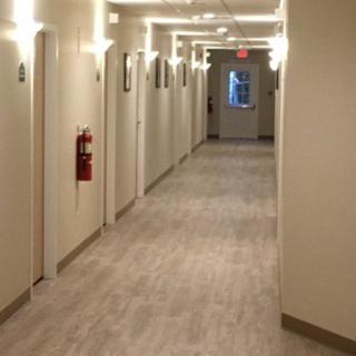 A well-lit indoor hallway with multiple doors and a fire extinguisher on the wall.
